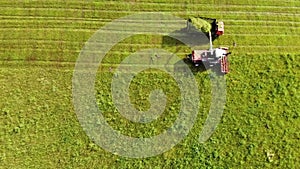 Aerial photography. Wide and close-up shots of a harvester cutting green grass. Birds of prey swirl over cars. The concept of sust