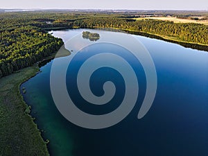 Aerial of a picturesque lake surrounded by forests with leafy trees