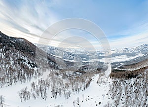 Aerial Picturesque panoramic landscape in the Altai mountains with snow-capped peaks under a blue sky with clouds in winter with