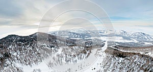 Aerial Picturesque panoramic landscape in the Altai mountains with snow-capped peaks under a blue sky with clouds in winter with
