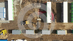 Aerial of powerful yellow excavator digging trench with bucket. Laying of underground power cables in red flexible