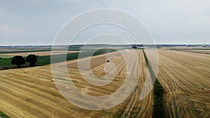 Aerial pullback shot over a wheat field Combine harvester harvesting