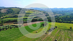 Aerial push-in shot from Belmonte Piceno in the Fermo province of Marche region, Italy, with fields, hay bales, hillscape