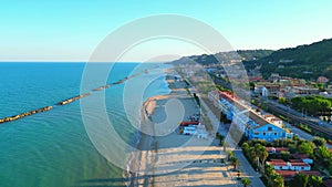 Aerial push-in shot from Cupra Marittima (Ascoli Piceno) with breakwaters, waves, beach, palms, buildings