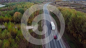 Aerial rear side view of semi truck moving along a highway with cargo trailer.