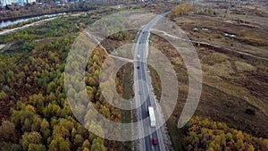 Aerial rear side view of semi truck moving along a highway with cargo trailer.