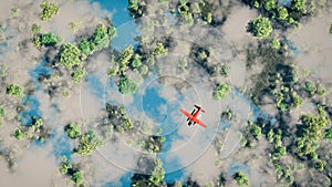 Aerial of red airplane flying over forest with lakes.