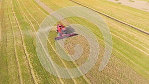 Aerial of red combine harvester working on large wheat field