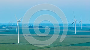 Aerial red lights on wind turbines at dusk on hazy evening over farmland