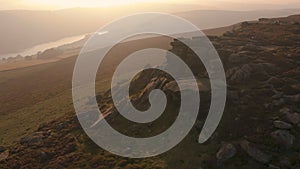 Aerial rotate around rocks sticking out the Peak District National Park during an amazing sunset