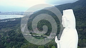 Aerial round motion white buddha statue head against hills