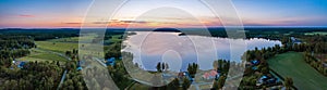 Aerial Scenic panorama of midnight Sun in Northern Sweden, middle summer light nights, polar region. Red orange sky, blue lake,
