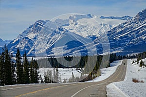 AERIAL: Scenic view of the snowy Rockies as car disappears in the distance.