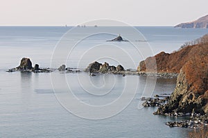 Aerial seascape of Peter The Great Bay in sunny autumn day in sunrise. Calm blue water, rocky capes and islands with lighthouse, s