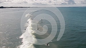 Aerial shoot of the sea waves with foam and surfers