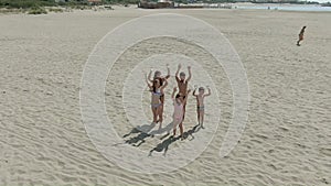 Aerial shooting of cheerful children children holding hands on the beach