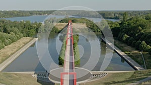 Aerial shooting of a conceptual bridge with red arches on the Oise River