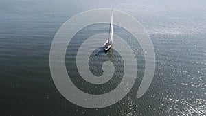 Aerial shooting of a sailing yacht in the sea. Sunny day at sea. Man and woman sailing on yacht at the sea