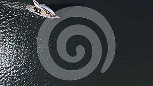 Aerial shooting of a sailing yacht in the sea. Sunny day at sea. Man and woman sailing on yacht at the sea