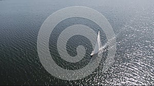 Aerial shooting of a sailing yacht in the sea. Sunny day at sea. Man and woman sailing on yacht at the sea