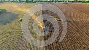 Aerial shot of agricultural field with tractor pulling a disc harrow over agricultural field, farmland