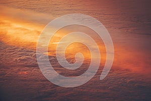 Aerial shot from the airplane window of the sky above the clouds illuminated by sun rays