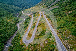 Aerial shot of an asphalt road on a green mountain near the river