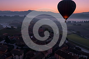 aerial shot of balloon ascending over a sleepy town at dawn