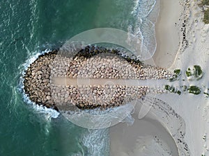 Aerial shot of a beach, featuring rocks and crystal-clear blue water