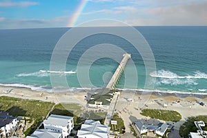 aerial shot of the blue ocean water along the coastline at Johnnie Mercer\'s Fishing Pier with homes, people on the sand