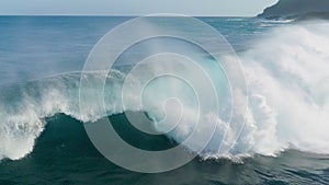 Aerial shot of breaking surf with foam in Pacific Ocean. Drone Slow motion barreling wave with texture and wind spray