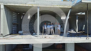 Aerial shot of builders team on construction site discussing plan of project with architect and contractor using