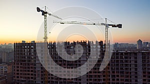 Aerial Shot of the Building in the Process of Construction. Labor working in big construction site. In the Background