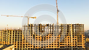 Aerial Shot of the Building in the Process of Construction. Labor working in big construction site. In the Background