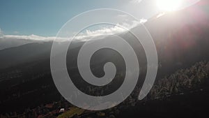 Aerial shot. Camera movement backwards. At sunset in the mountains. Against the backdrop of a dark green forest of trees