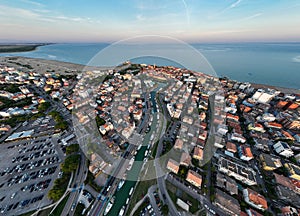 Aerial shot of a Caorle, the Resort sea beach city near to Venice. Fisherman boats in lagoon at sunset time