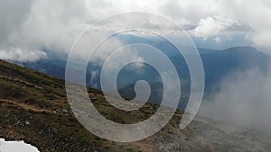 Aerial shot of the Carpathian Mountains covered with snow, grass and clouds.