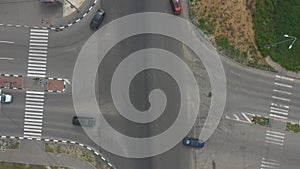 Aerial shot of cars passing through crossroad in city area. Drone flying over urban highway with busy auto traffic. Top