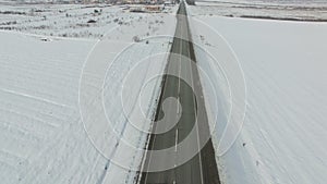 Aerial shot of cars and trucks driving on a road on winter sunny day.