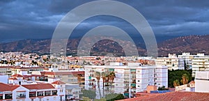 Aerial shot of a city with white blocky buildings under dark clou