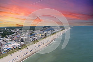 aerial shot of the coastline with the Carolina Beach Boardwalk, homes, hotels and restaurants with people relaxing in the sand