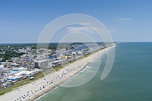 aerial shot of the coastline with the Carolina Beach Boardwalk, homes, hotels and restaurants with people relaxing in the sand