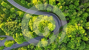An aerial shot of a curved road from above shot with a drone. Still camera, no shake. Just driving one car along the