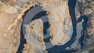 Aerial shot of a curvy river surrounded by trees and field under the sunlight in Tipu, Estonia