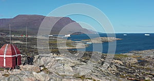 Aerial shot of drone pulling back from Arctic Island with two tourist guys waving at camperia in Disko Bay Disko Island