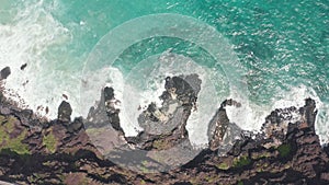 Aerial shot from drone. Top view on the rocky ocean shore. Blue Waves of the Pacific Ocean is crashing on the rock