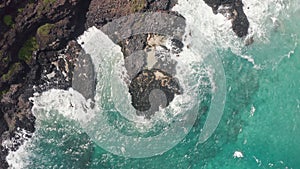 Aerial shot from drone. Top view on the rocky ocean shore. Camera rotates 360. Blue Waves of the Pacific Ocean is