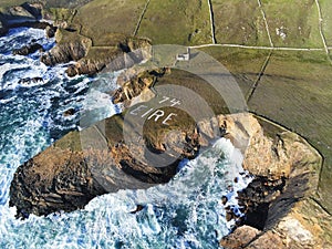 Aerial shot of Eire 74 Sign written on the surface of a coastal cliff