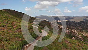 Aerial shot of electric car driving on the sunny road highway to mountains landscape.Luxury modern vehicle riding fast