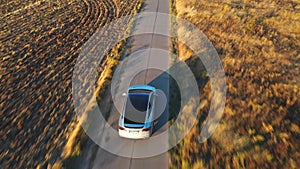 Aerial shot of electrical car driving on country road at sunny day. New SUV vehicle speeding along highway. Ecology